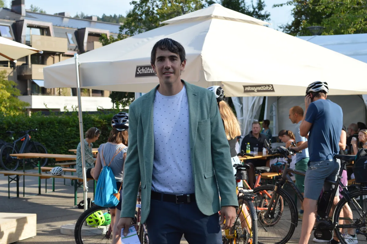 Ein Mann mit einem grünen Jacket steht vor Fahrrädern.